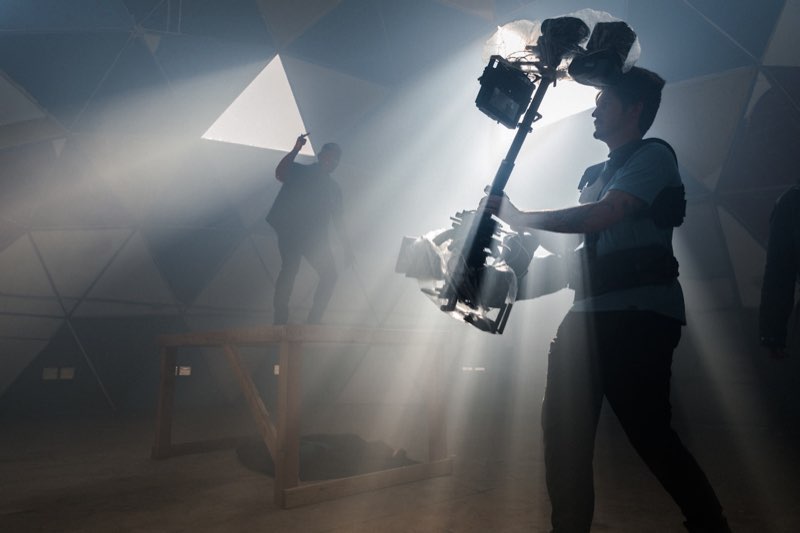 A gimbal operator in shafts of light through haze inside a dome.